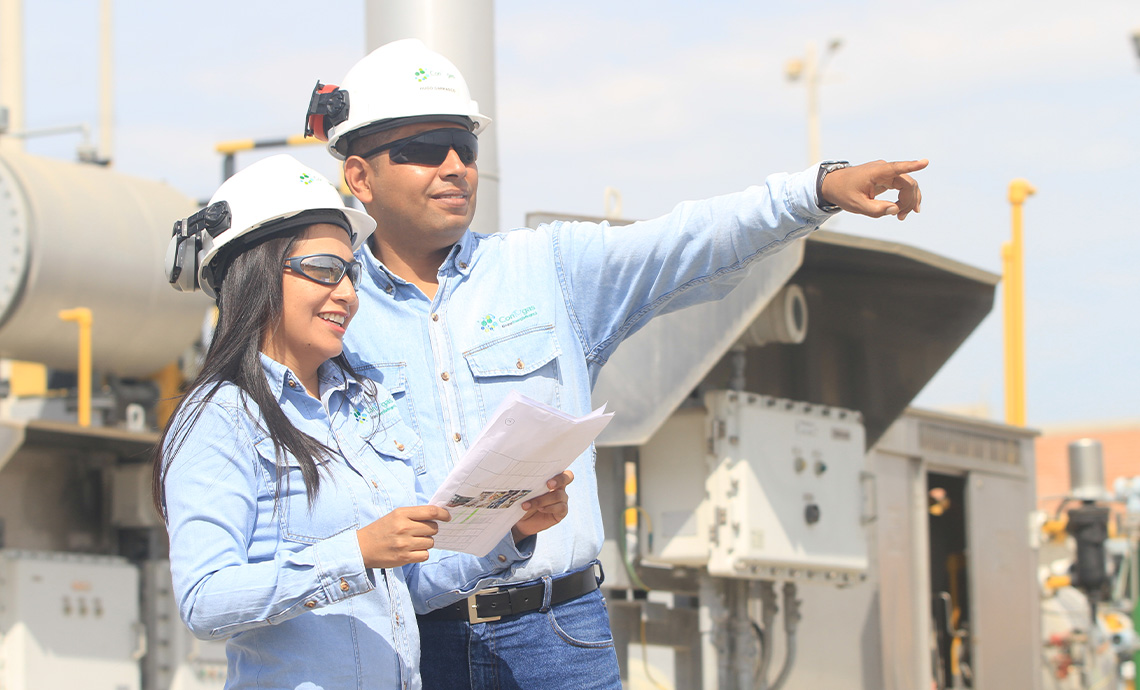 A worker points afar and a female worker smiles.