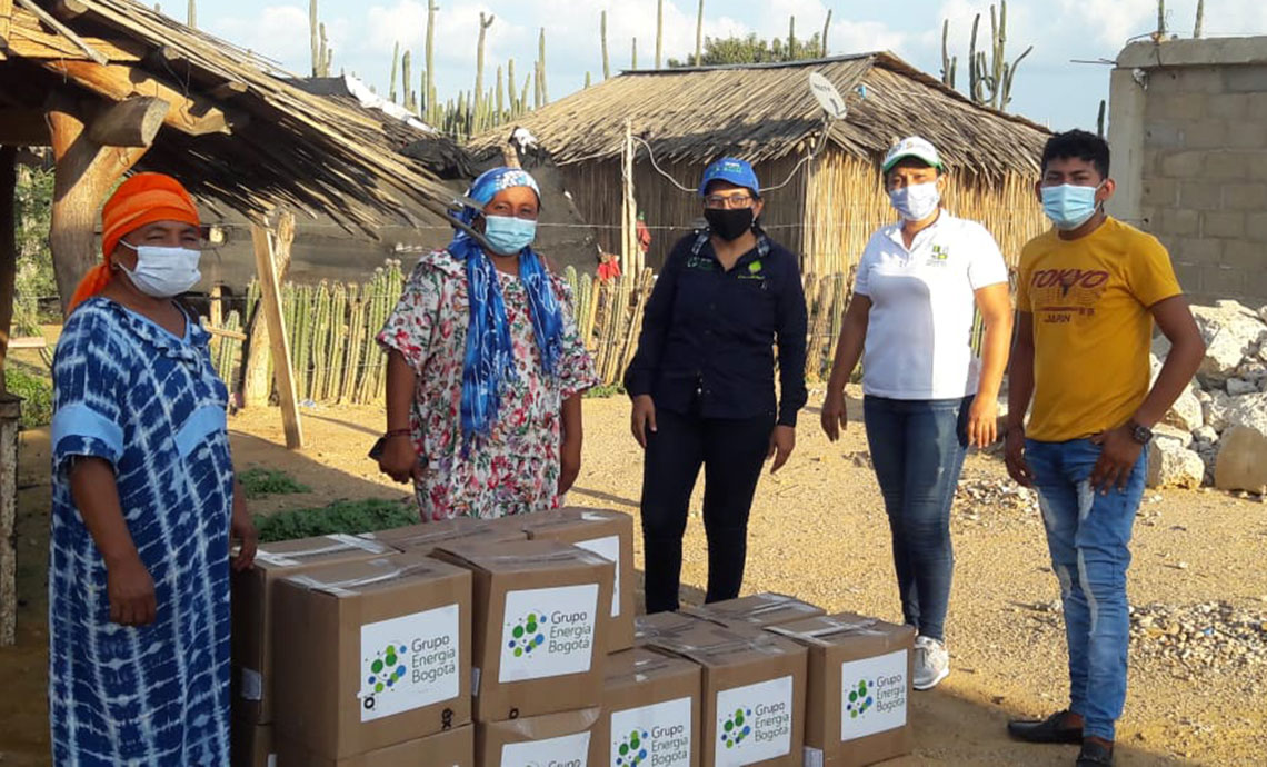 Two women and a young man from the Wayú community receive humanitarian aid packages from GEB.