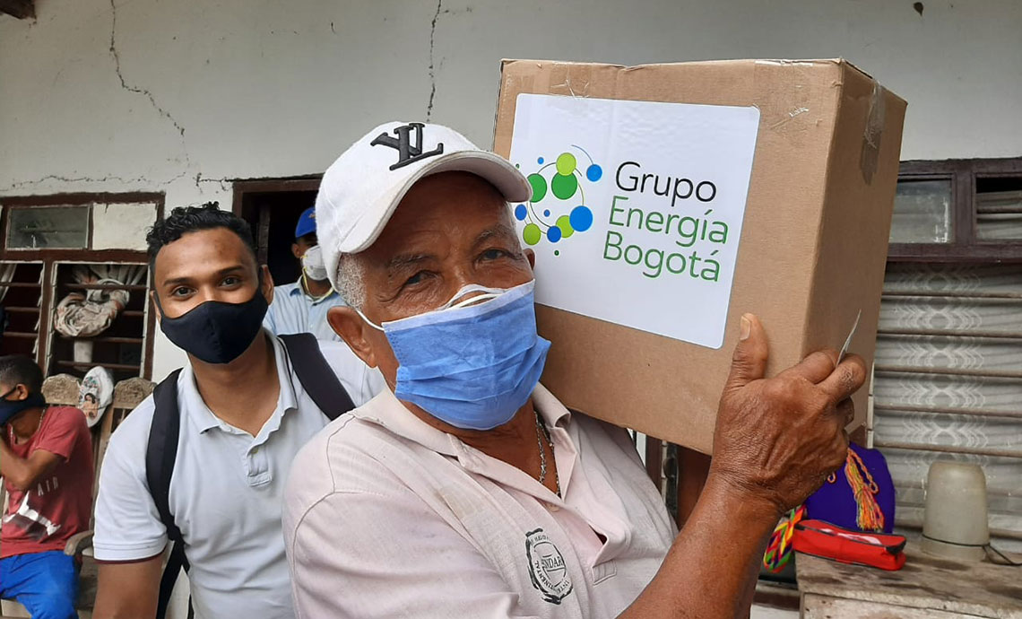 An older man carries a humanitarian aid package from GEB.