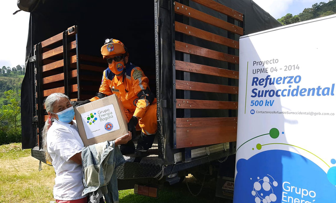 Older lady receives humanitarian aid package from GEB handed over by a Civil Defense member from a truck.