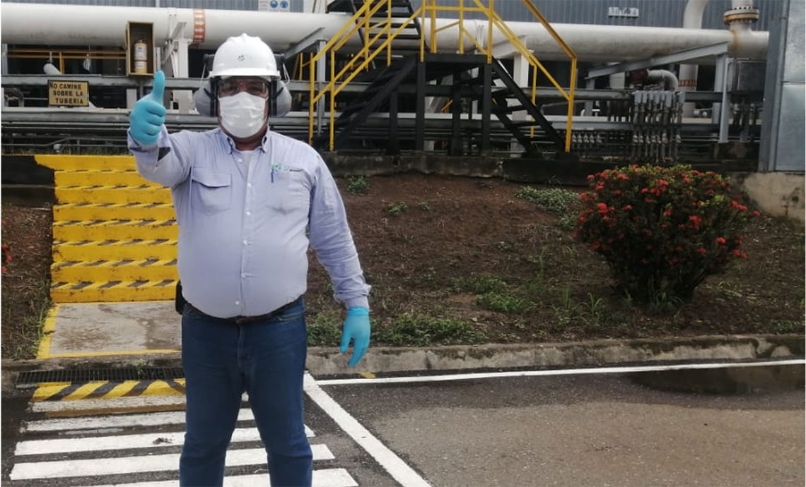 Worker at infrastructure wearing personal protection equipment gives thumb up with right hand.