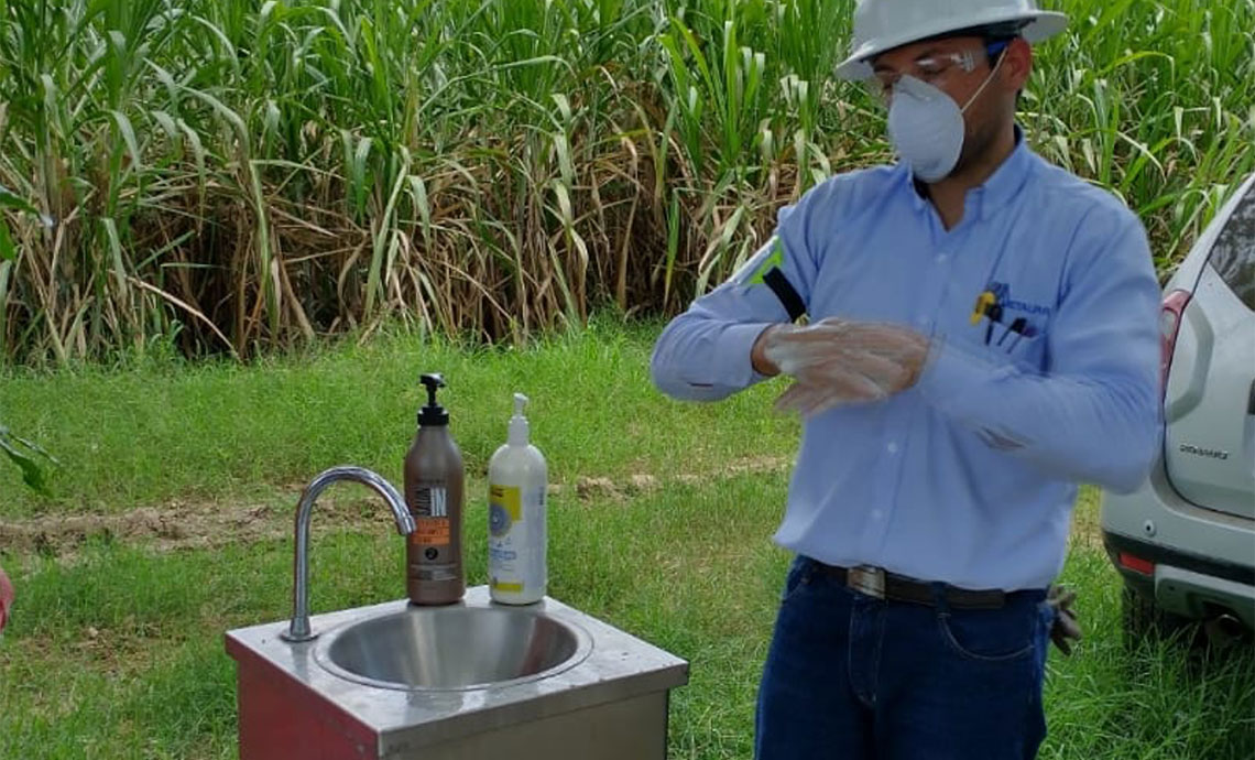 Worker washes hands with soap and water at portable sink.