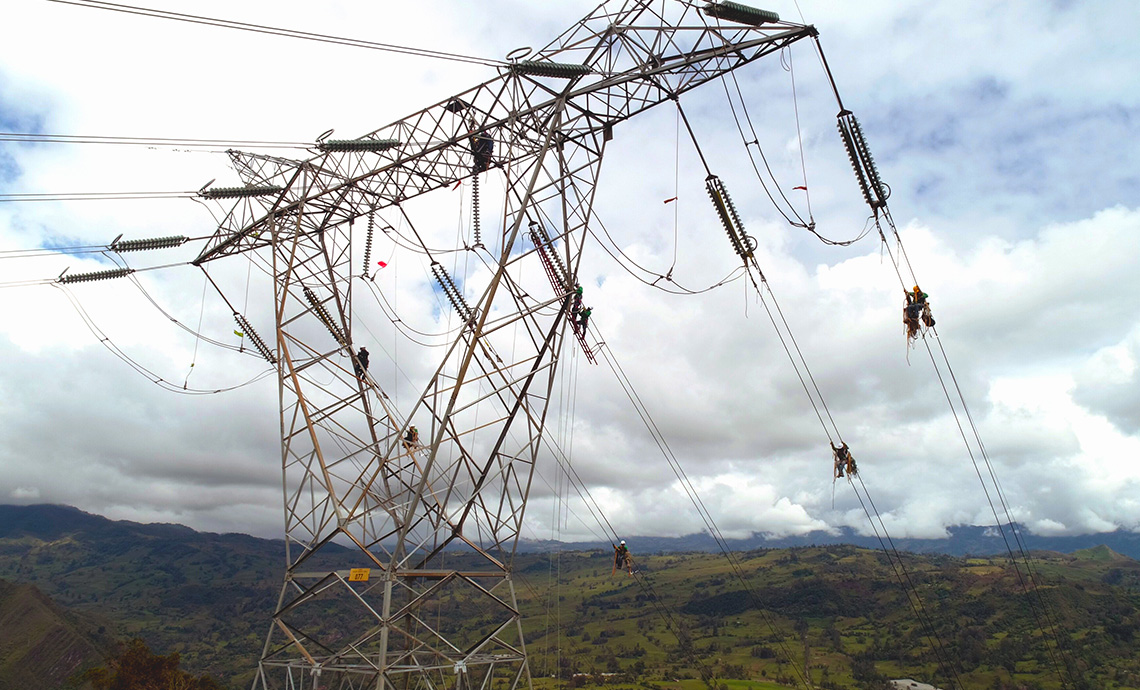 Employees working at heights on cables of an electric tower.