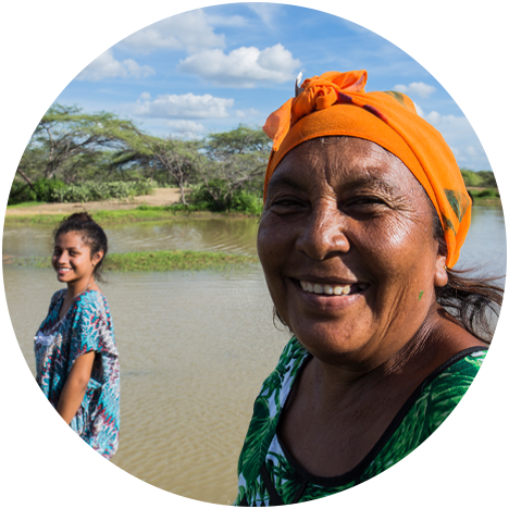 Two smiling women on a riverbank.